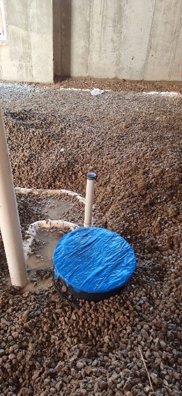 Sump pump basin installed in gravel sub-floor during new home construction