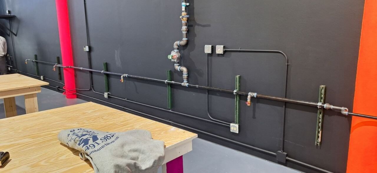 Black iron gas piping run along a commercial wall